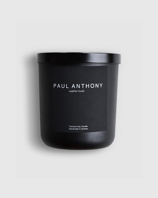 Black candle with 'Paul Anthony' branding on a light gray background