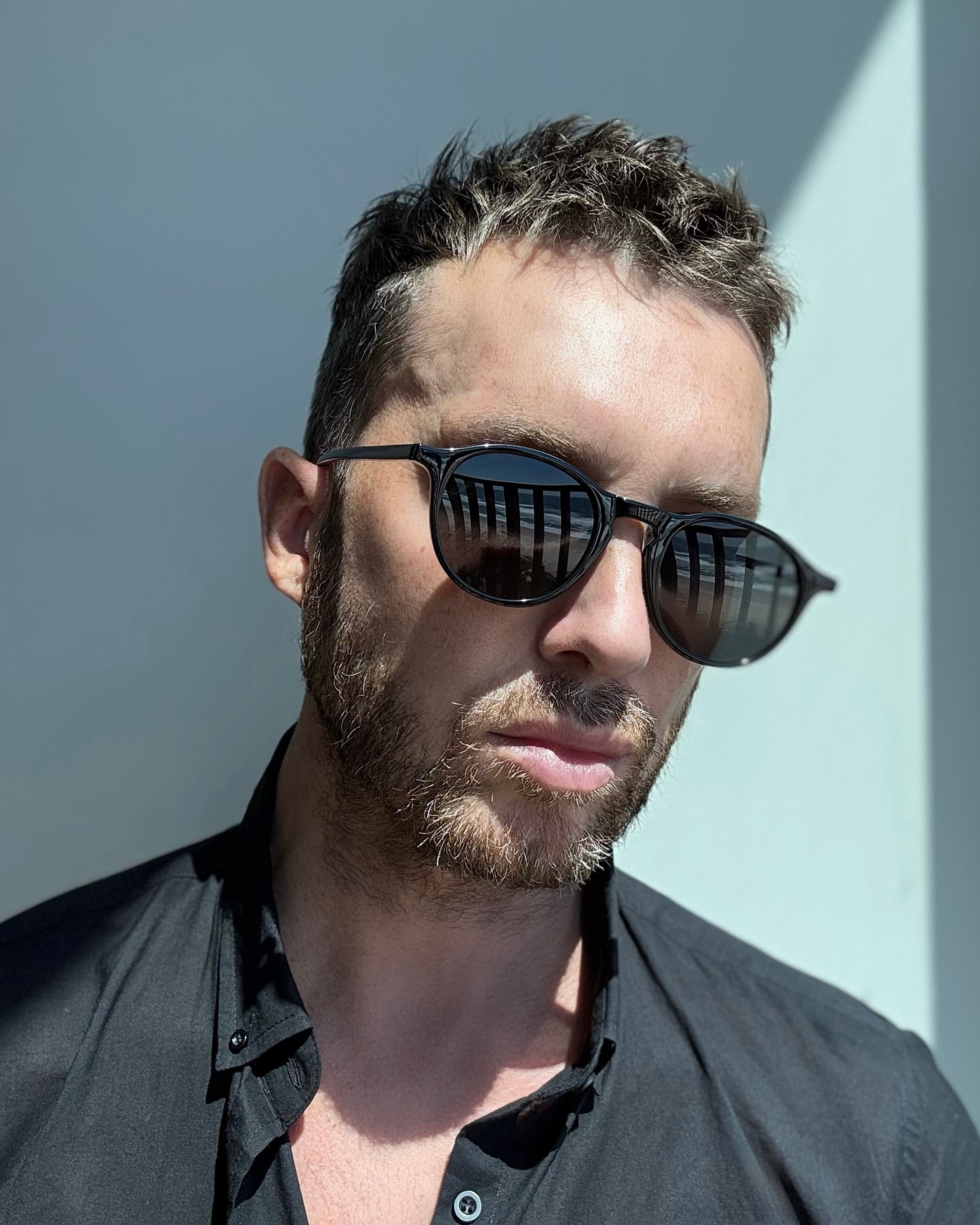 Man wearing BLACK sunglasses with a neutral background