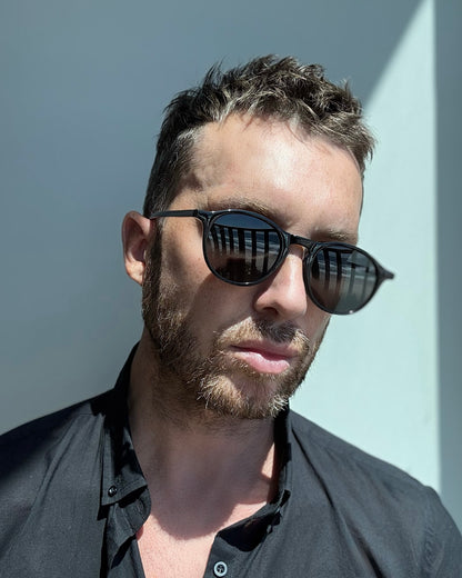 Man wearing BLACK sunglasses with a neutral background
