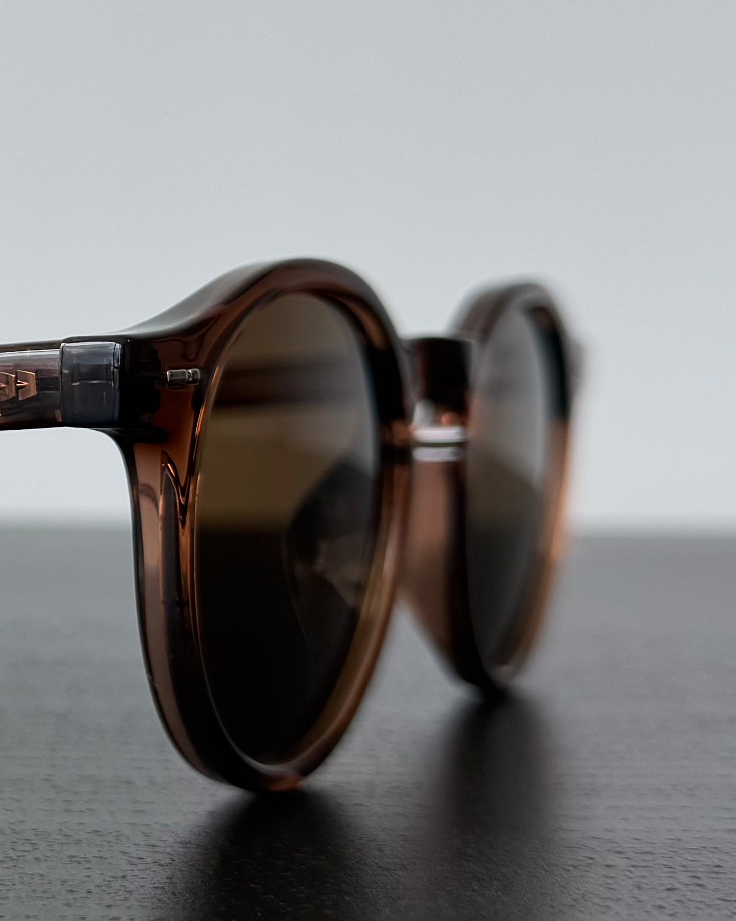 Brown sunglasses on a reflective surface with a blurred background